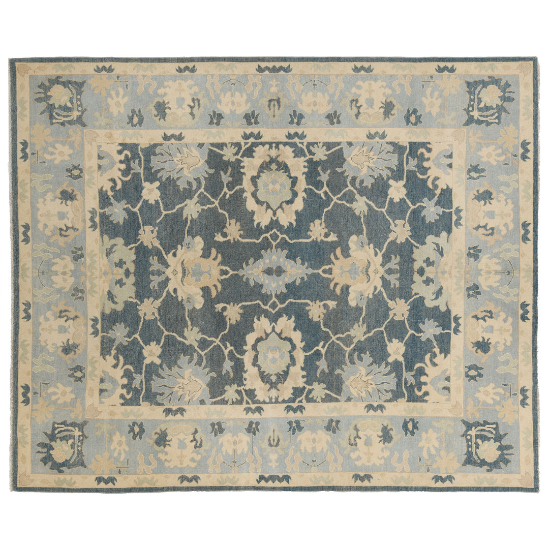 Hand-knotted 8x10 Oushak area rug featuring a traditional floral design in deep slate blue, cream, and light blue.