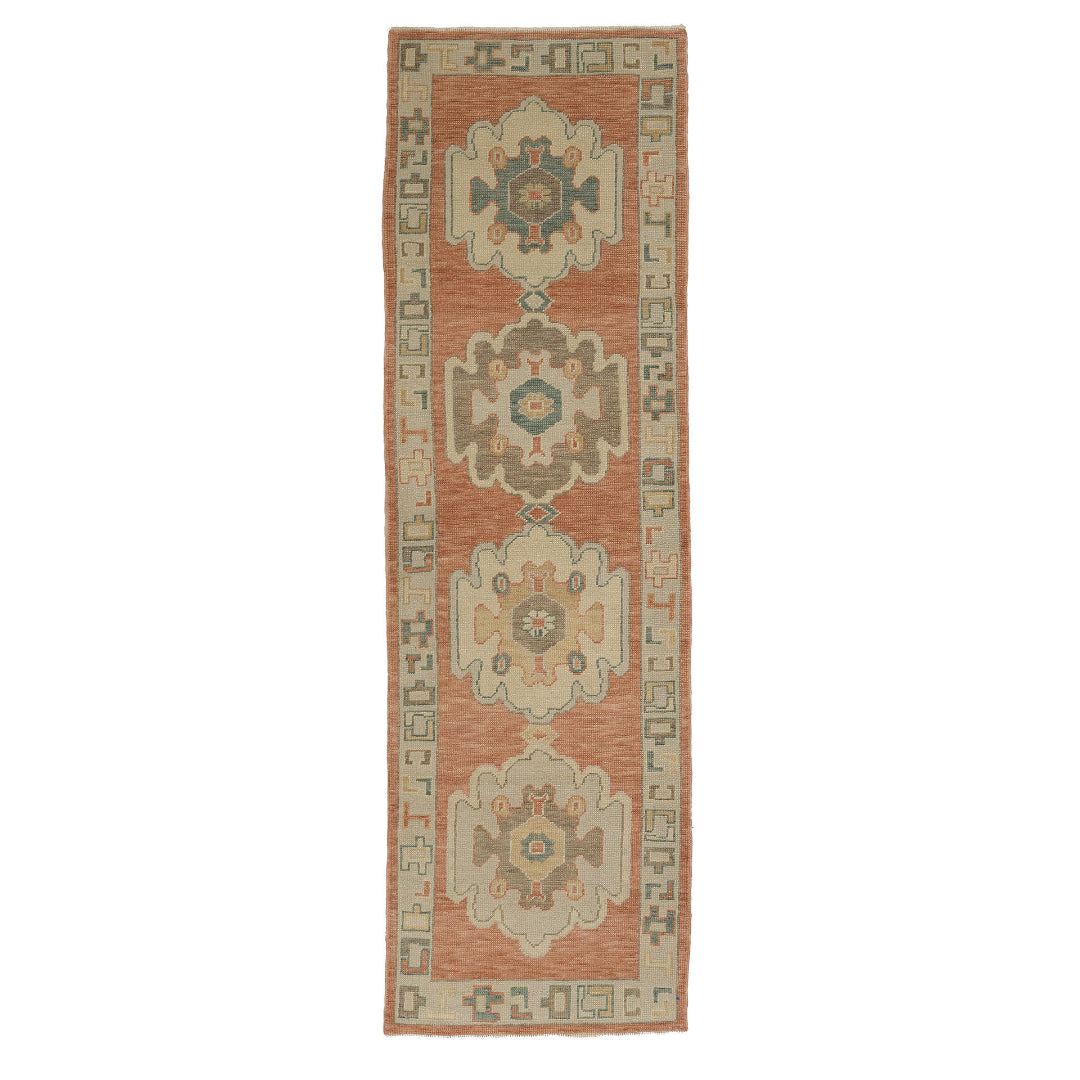 Warm terracotta Oushak area rug runner with stepped geometric medallions in cream, brown, and teal.
