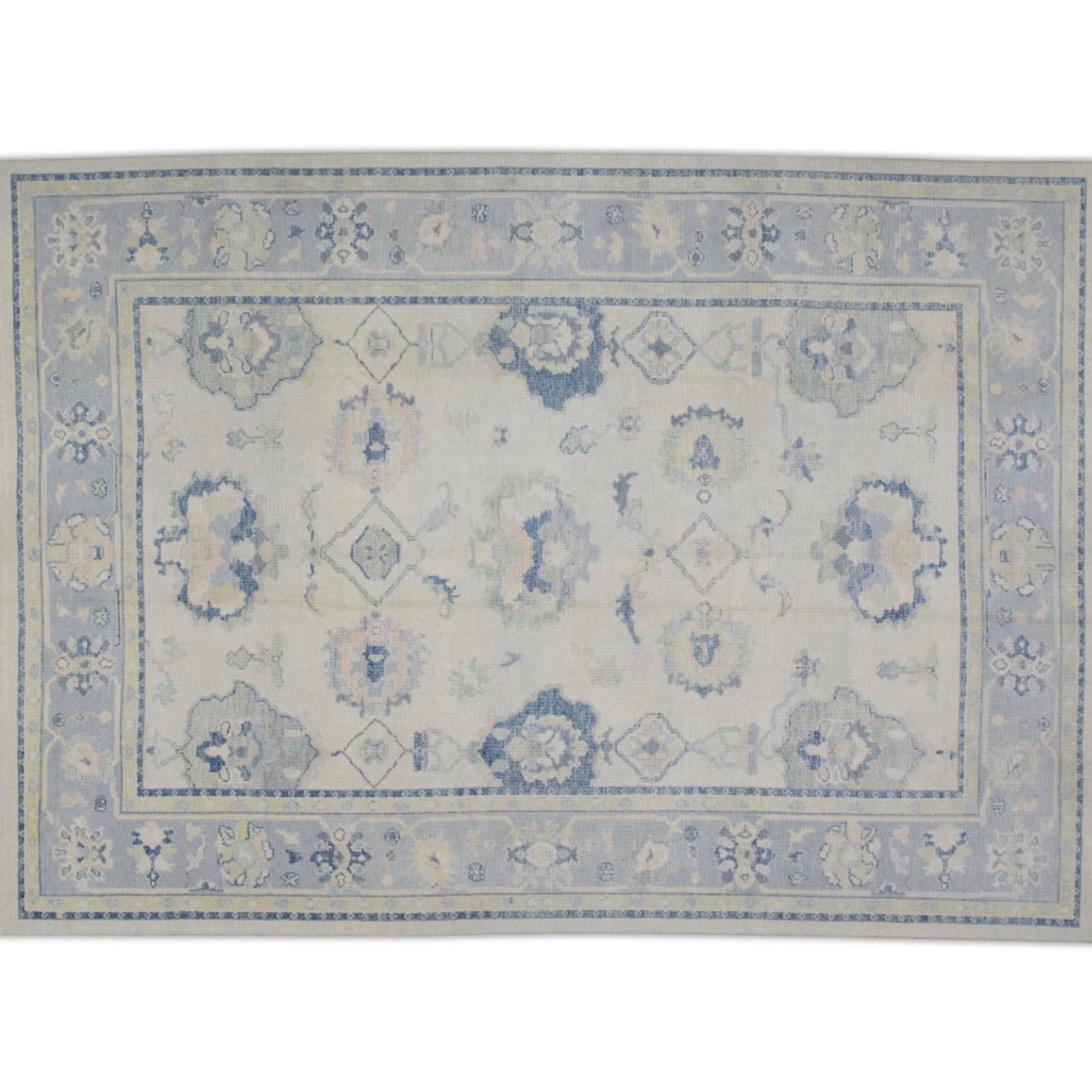 Soft beige 9x12 Oushak area rug with light blue border, green floral palmettes, and dark blue accents.
