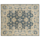 Hand-knotted 8x10 Oushak area rug featuring a traditional floral design in deep slate blue, cream, and light blue.