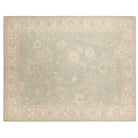 Muted pale blue-gray 9x12 Oushak area rug with cream floral palmettes and a wide cream border.