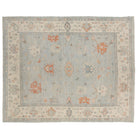 Hand-knotted 9x12 Oushak rug featuring a pale blue field with tangerine orange and cream botanical motifs.