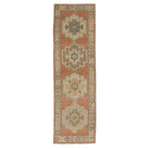 Warm terracotta Oushak area rug runner with stepped geometric medallions in cream, brown, and teal.