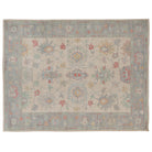 Hand-knotted 9x12 Oushak area rug featuring an ivory center field with rose and light blue geometric floral palmettes.