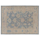 Hand-knotted 9x12 Oushak area rug with a rich slate blue center field, linen beige border, and soft coral accents.