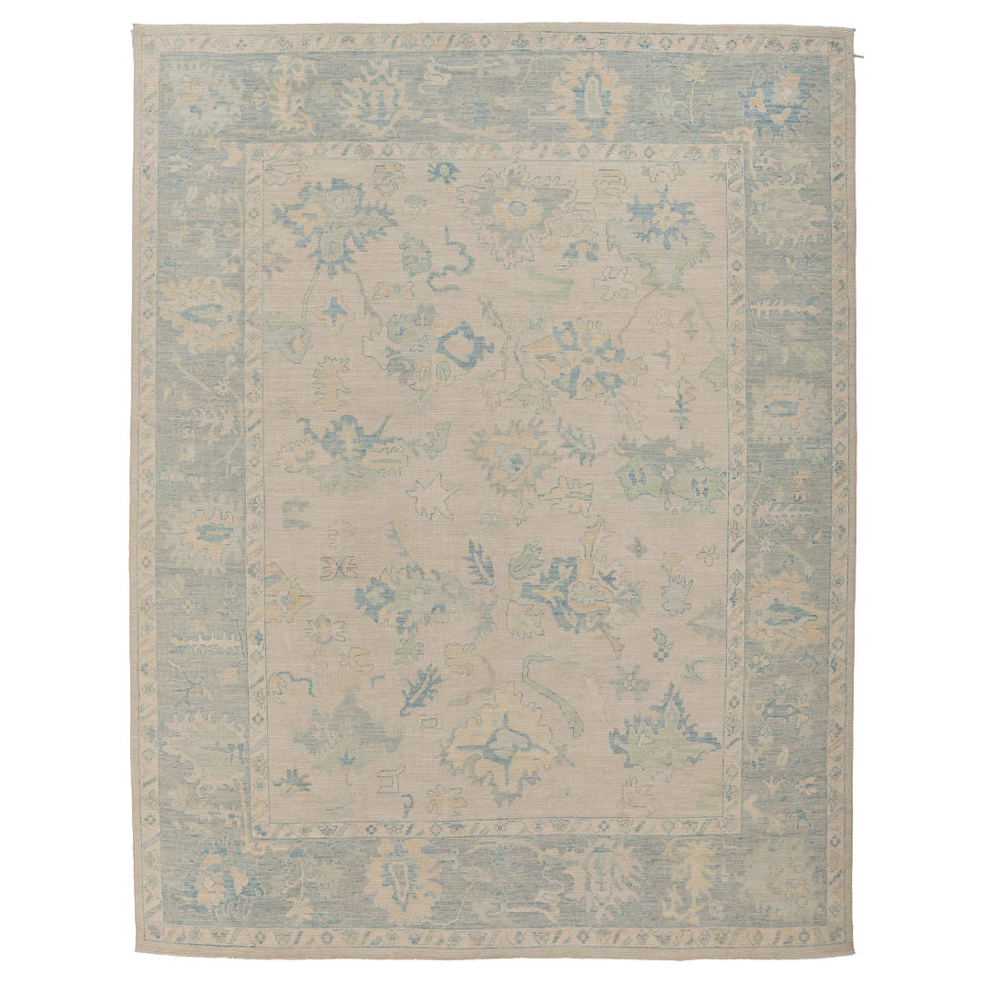 Hand-knotted 9x12 Oushak area rug with a soft ivory field, light blue botanical patterns, and a faded blue border.