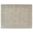 Hand-knotted 9x12 Oushak area rug with a soft ivory field, light blue botanical patterns, and a faded blue border.