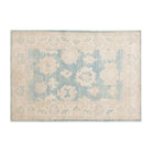 Denim blue 4x6 Oushak area rug with cream floral medallions and a wide ivory border.