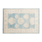 Vibrant medium blue 4x6 Oushak area rug with warm beige geometric star medallions and a distressed cream border.