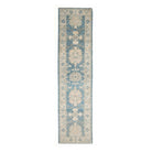 Long traditional Oushak runner rug displaying a dark blue field, ivory borders, and peach and light blue motifs.