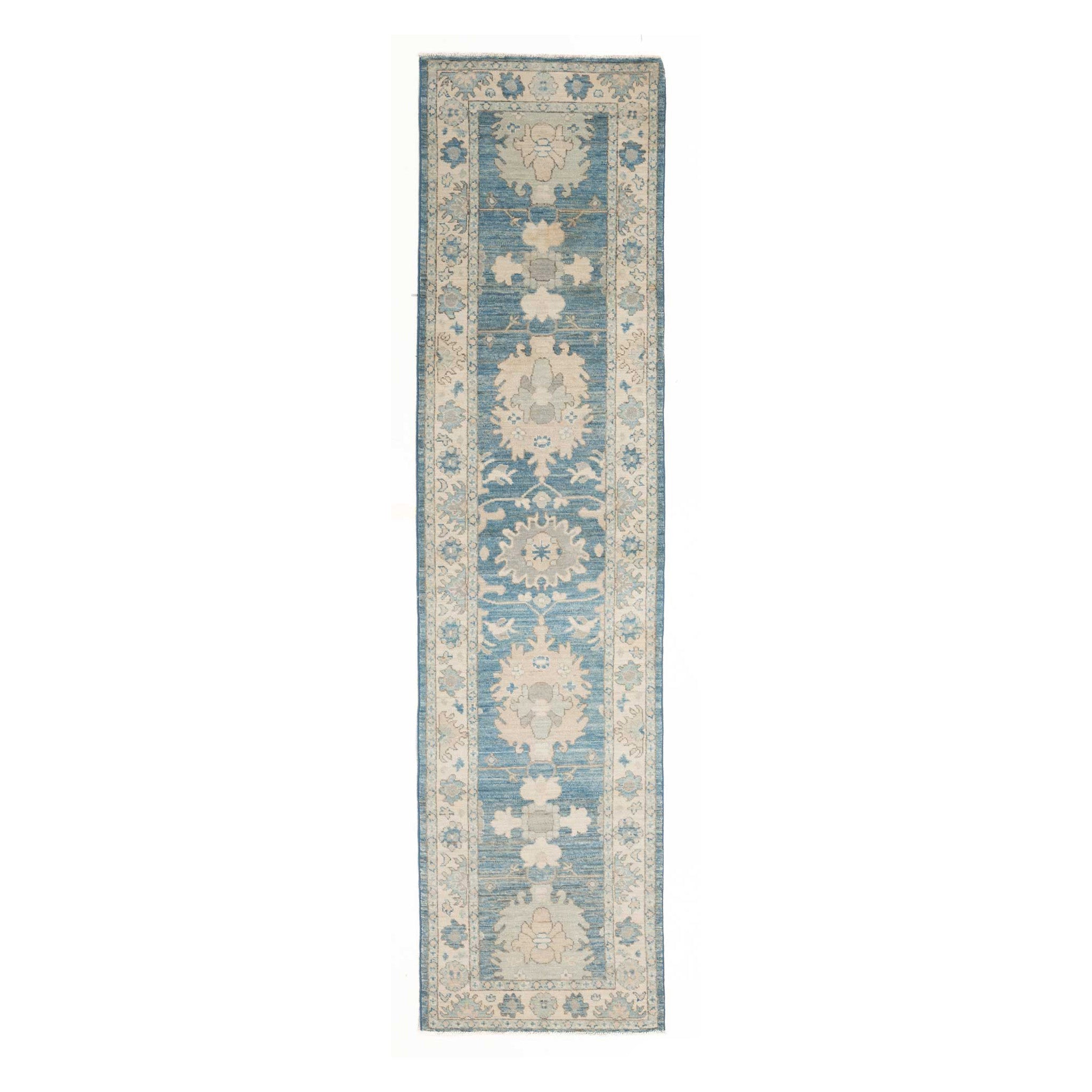 Long traditional Oushak runner rug displaying a dark blue field, ivory borders, and peach and light blue motifs.
