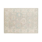Soft gray 5x7 Oushak area rug with pale blue and ivory floral medallions and a distressed border.