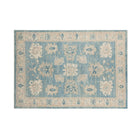 Rich slate blue 5x7 Oushak area rug with ivory cream floral palmettes and a wide cream border.