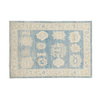 Traditional medium blue 4x6 Oushak area rug with warm beige and ivory geometric medallions and a distressed cream border.
