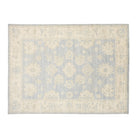 Soft periwinkle blue 9x12 Oushak area rug with ivory floral palmettes and a wide cream border.