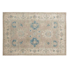 Warm caramel and taupe 5x7 Oushak area rug with teal blue floral medallions and a wide cream border.