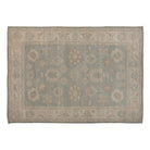 Soft green 10x14 Oushak area rug with ivory floral palmettes and a wide beige border.
