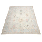 Ultra-faded ivory cream 8x10 Oushak area rug with lavender, salmon, and brown geometric star medallions.