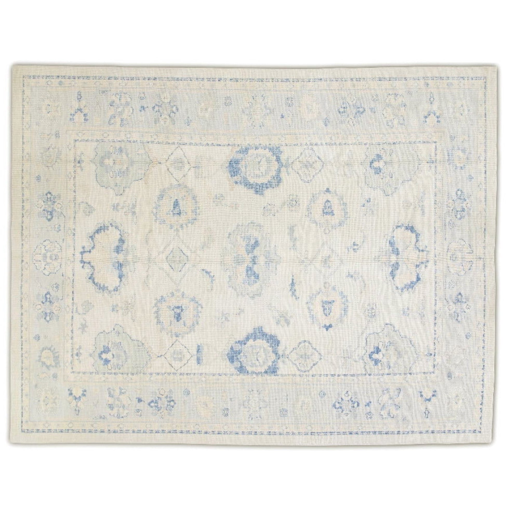 Luminous butter cream 9x12 Oushak area rug with medium blue floral medallions and blush pink accents.