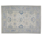 Soft beige 9x12 Oushak area rug with light blue border, green floral palmettes, and dark blue accents.