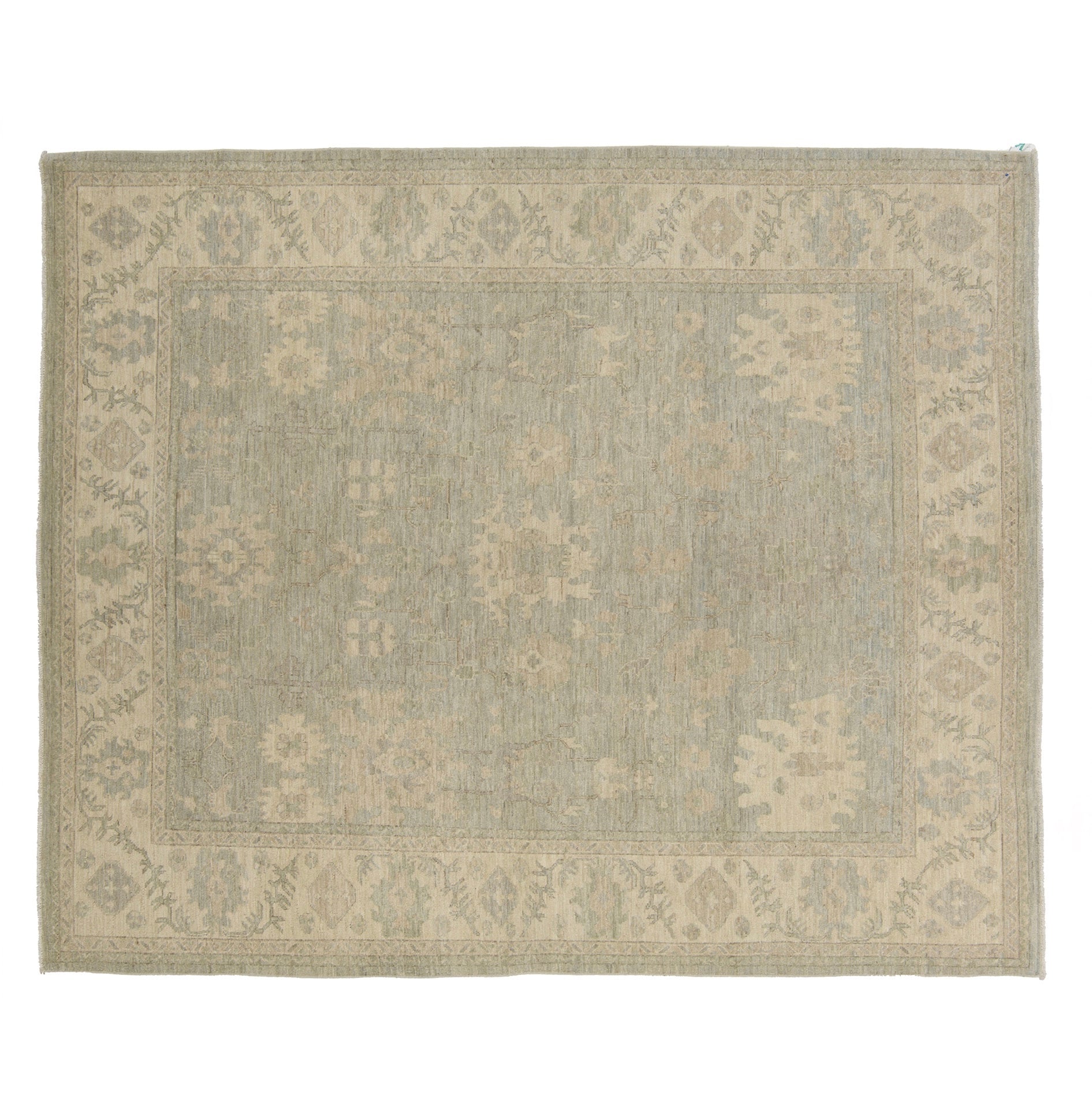 Muted mist blue 8x10 Oushak area rug with warm tan and cream floral motifs and a distressed border.