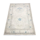 Muted ivory and sand 3x4 Oushak accent rug with soft blue geometric star medallions and a neutral border.