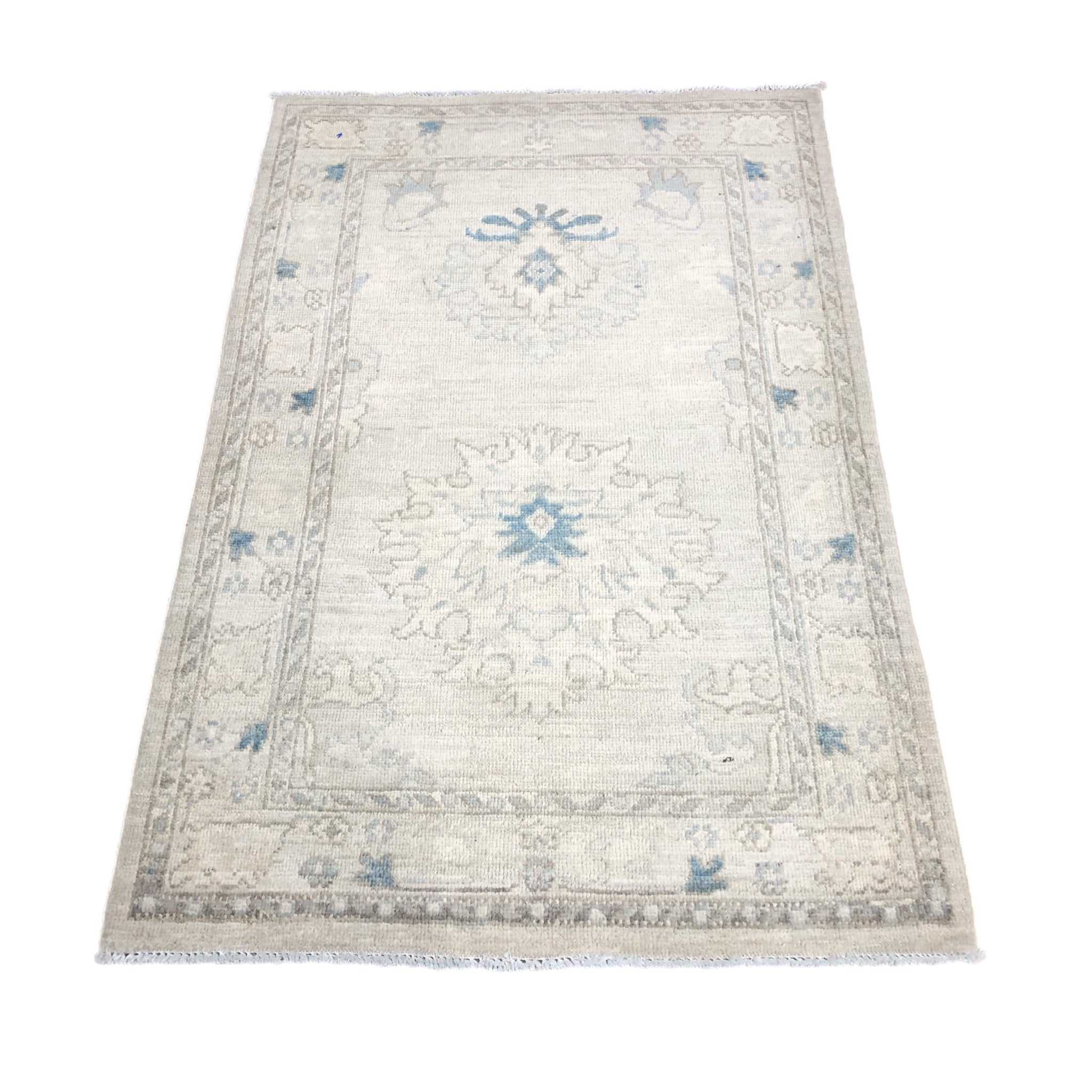 Muted ivory and sand 3x4 Oushak accent rug with soft blue geometric star medallions and a neutral border.